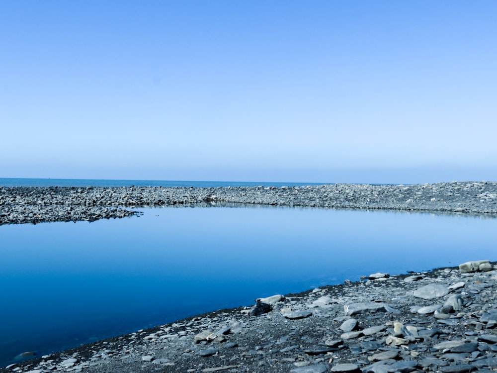 a rocky beach with water and blue sky