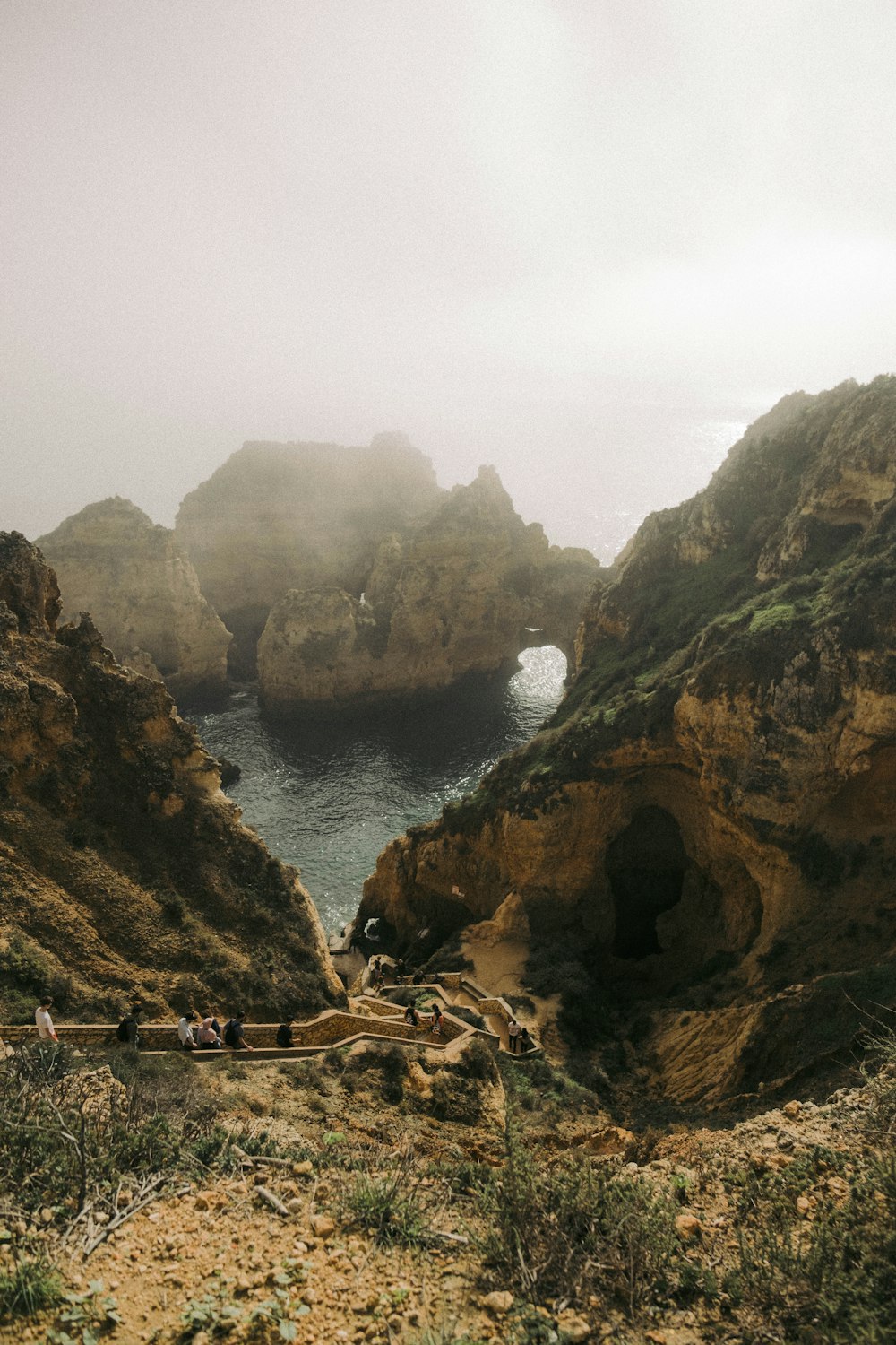 a group of people standing on a cliff over a body of water