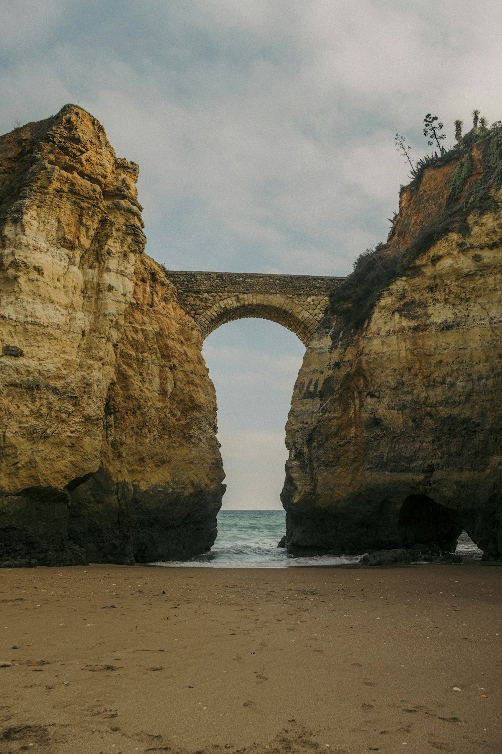 a large rock arch over a beach