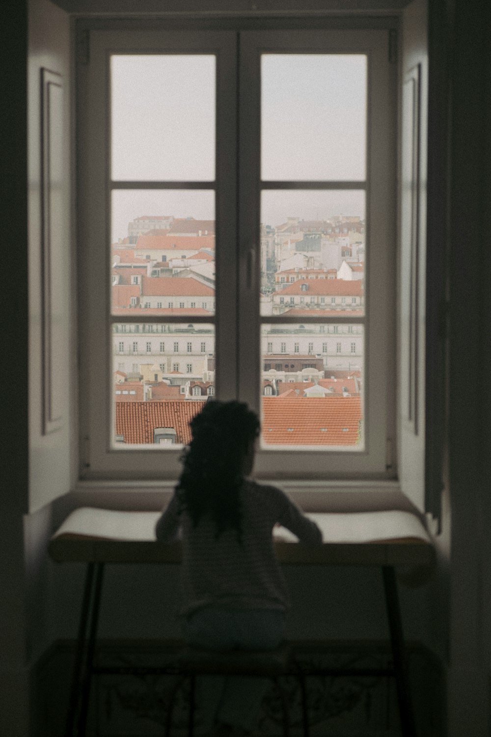 a person sitting at a desk looking out a window