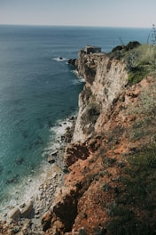 a rocky cliff next to a body of water
