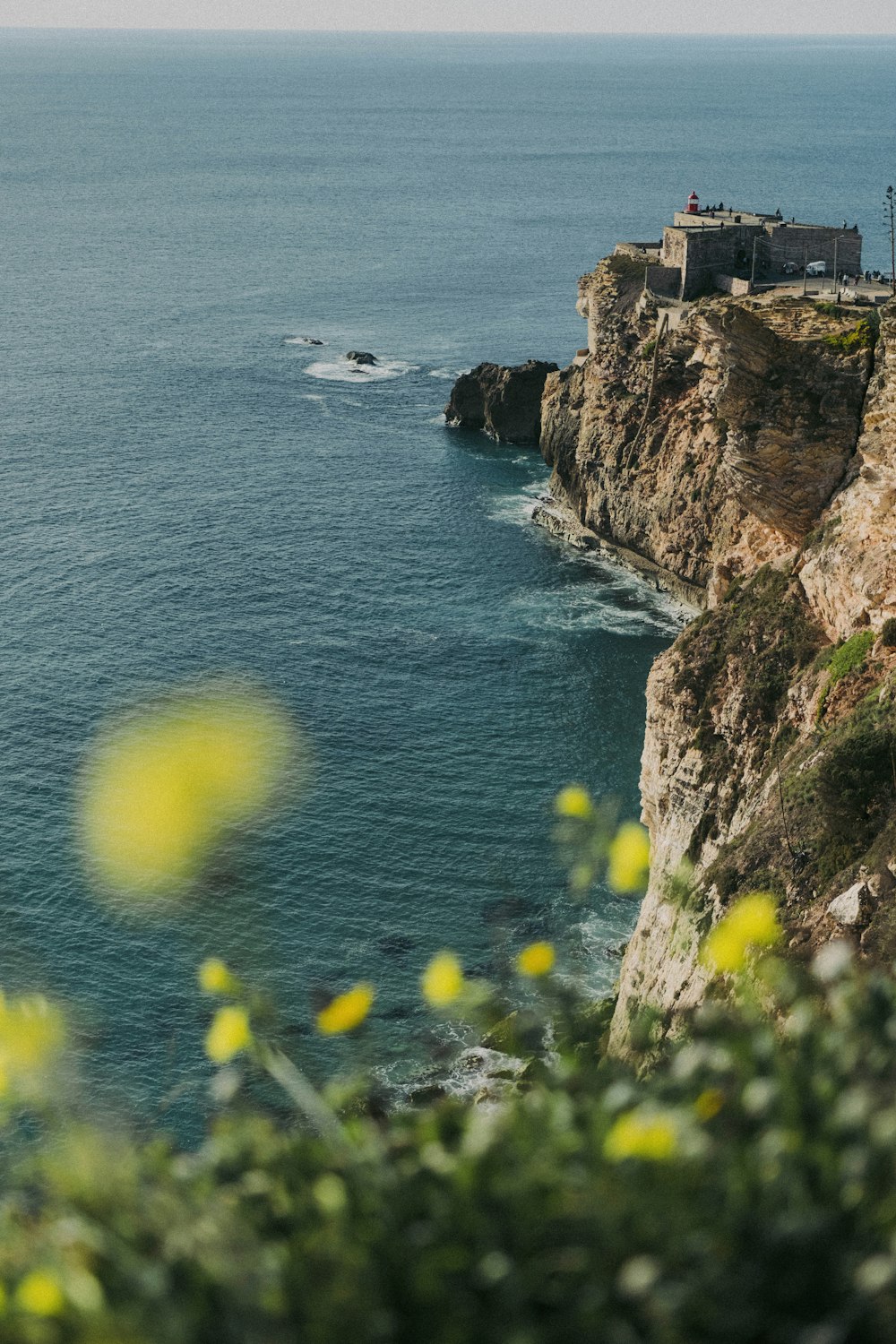 a cliff with a building on it by the water