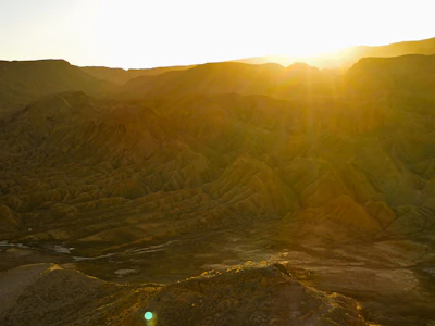 Golden sunset casting long shadows over a rugged desert landscape with distant mesas.
