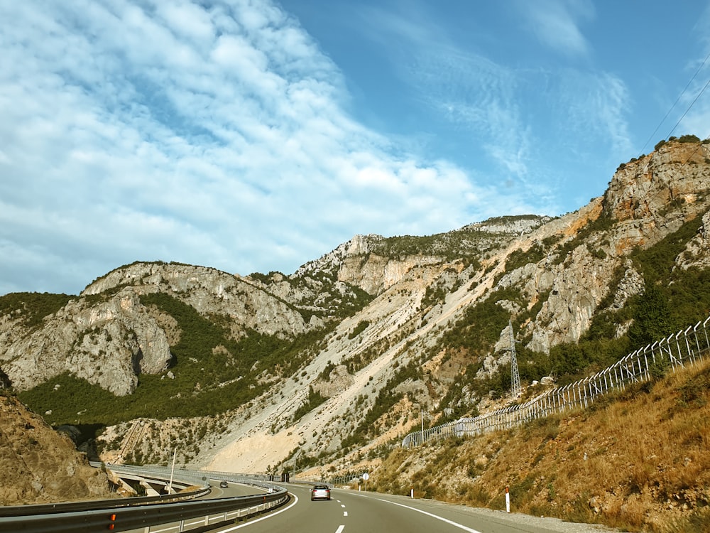 Una carretera con un coche y montañas en la parte trasera