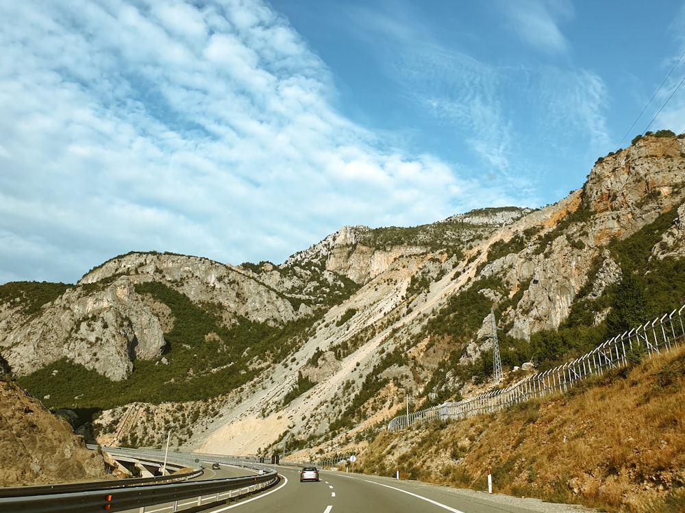 a road with a car on it and mountains in the back