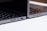Two sleek, modern laptops positioned back-to-back on a light surface, showcasing the sleek edges and ports of the devices. The keyboards are partially visible, and the lighting highlights the metallic texture of the laptops.