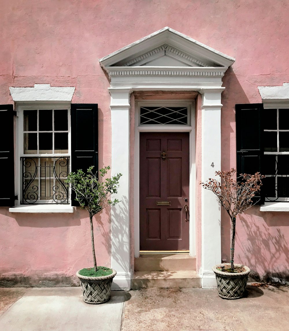 a pink house with a couple of plants in front of it