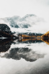 A serene view of Mount Fuji reflected in a calm lake with autumn foliage.