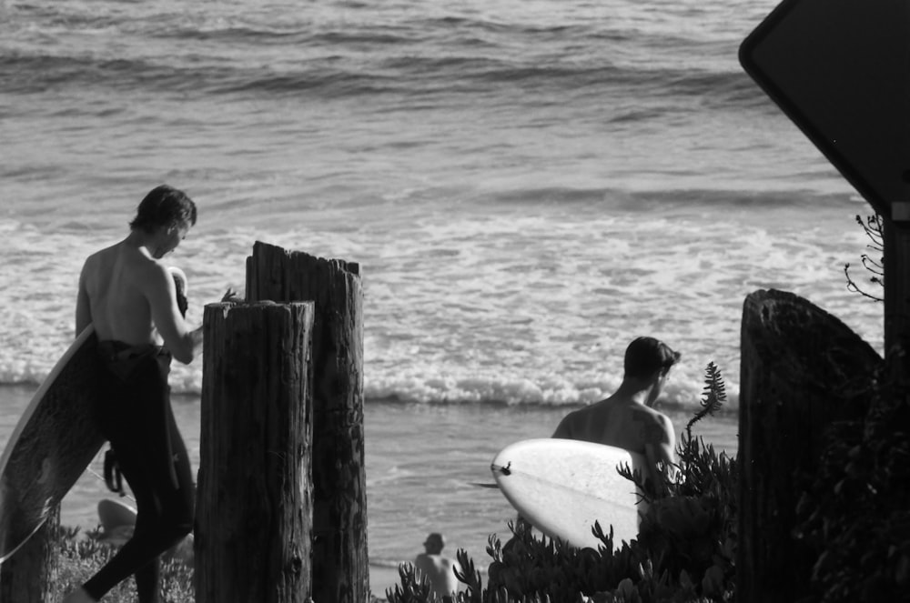 a couple of men stand near each other holding surfboards