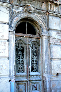 An old rustic wooden door with peeling paint and intricate ironwork details.