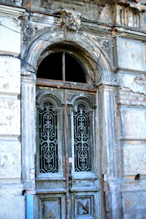 An old rustic wooden door with peeling paint and intricate ironwork details.