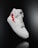 A white high-top sneaker prominently displayed against a dark background. The shoe features a distinctive red lightning bolt design on the side and is styled with white laces. The overall look is clean and modern, highlighting the shoe's sleek design and details.