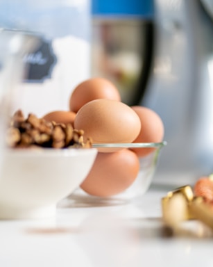 Close-up of various egg powders in bowls with fresh eggs on a rustic wooden table.