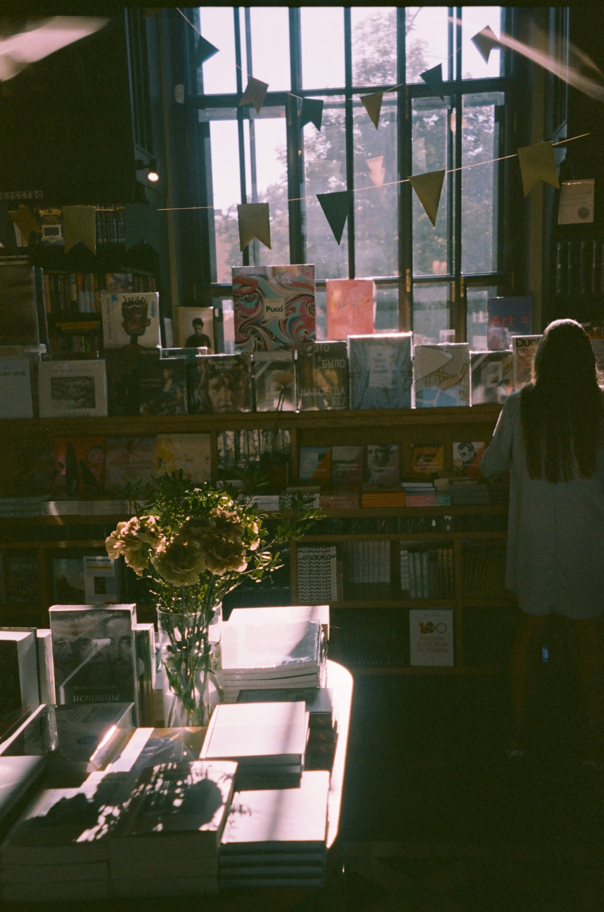 a person standing in front of a window with books on it