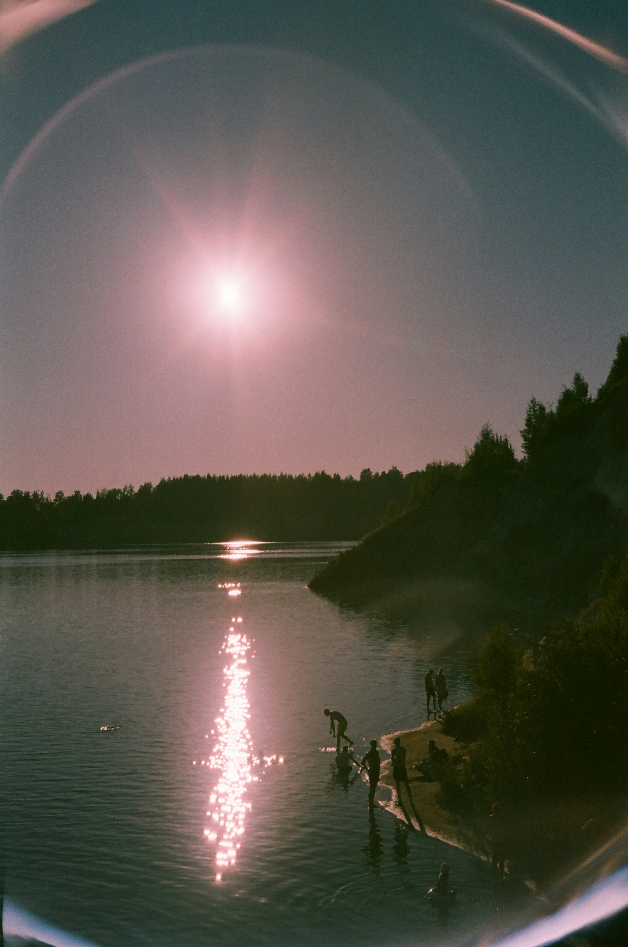 a body of water with a bright light in the sky above it