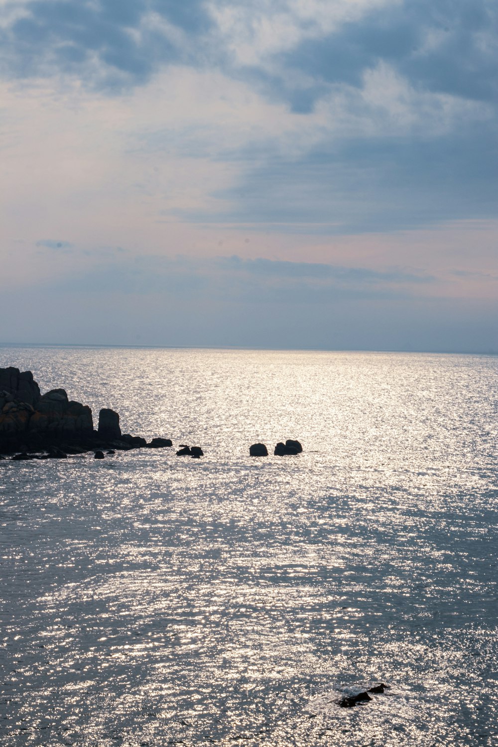 a body of water with rocks and a cloudy sky