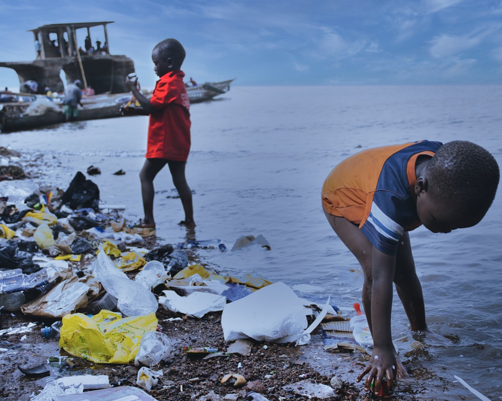 a person and a child standing on a beach with garbage