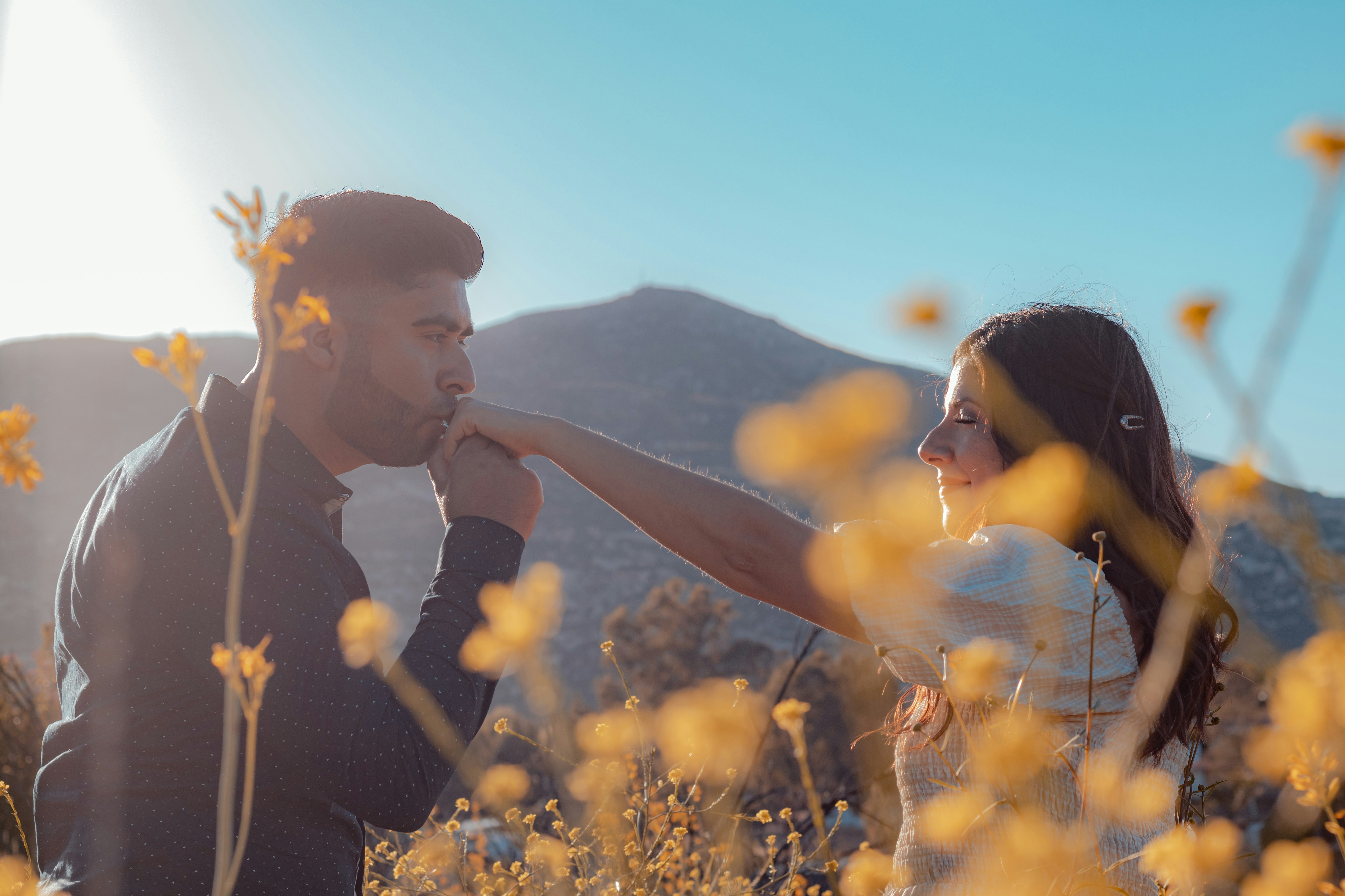 a man and woman holding hands in a field of flowers