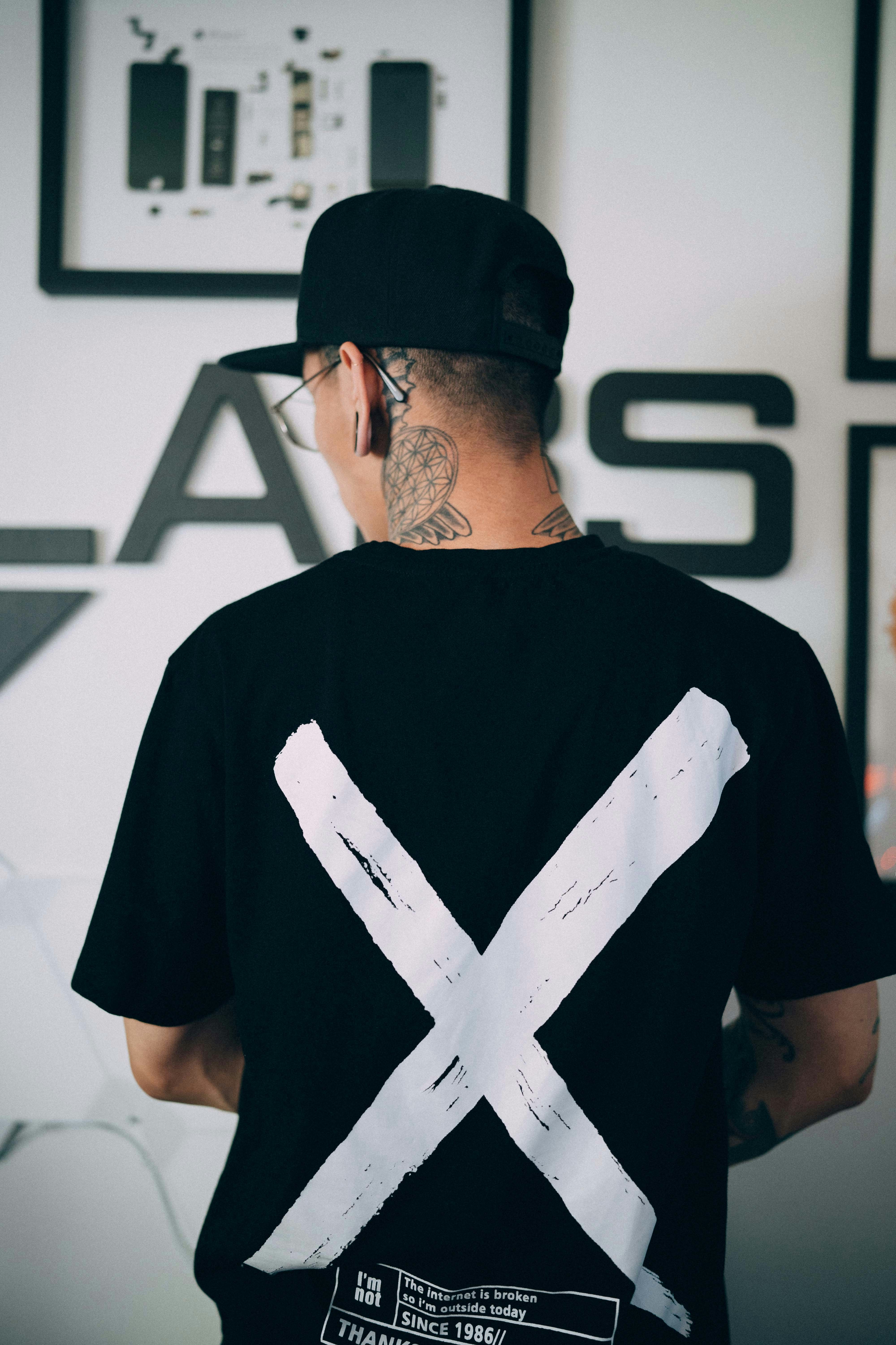 Oversized white graphic tee on dark hanger against black wall, street fashion aesthetic