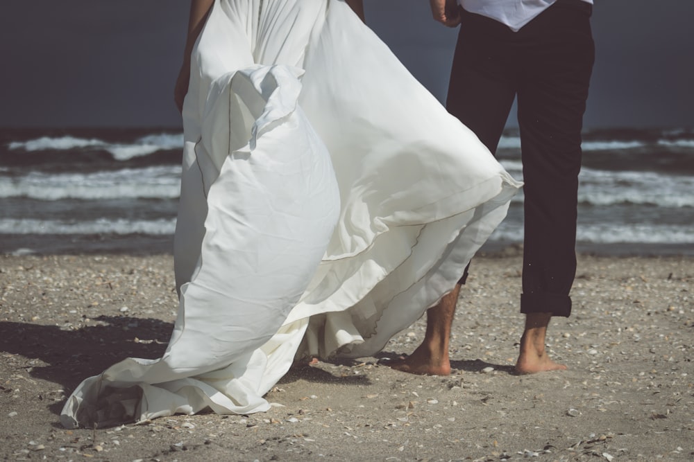 a man and woman holding hands on a beach