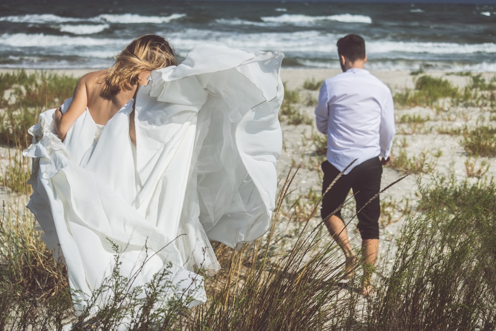 a man and woman holding a white sheet over a beach