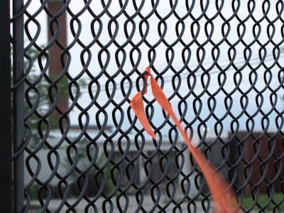 Installation of privacy tape on a chain link fence by workers outdoors.