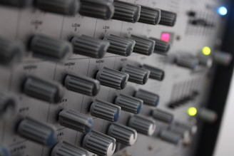Close-up of a professional radio mixer with colorful knobs and sliders in a studio.