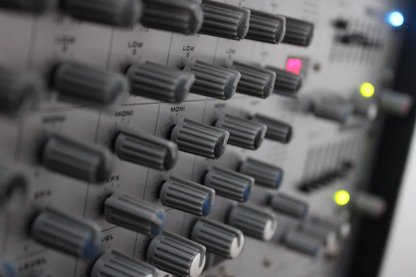 Close-up of a professional audio mixer with illuminated controls in a studio setting.