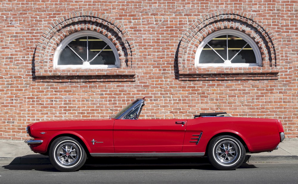 a red car parked in front of a brick building