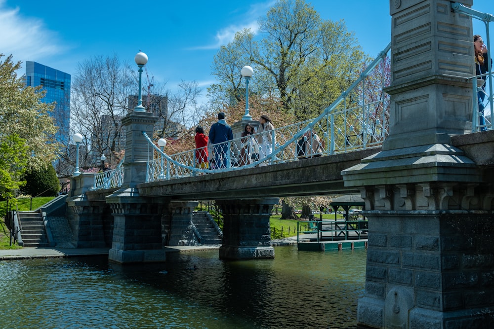 a group of people walking on a bridge over water