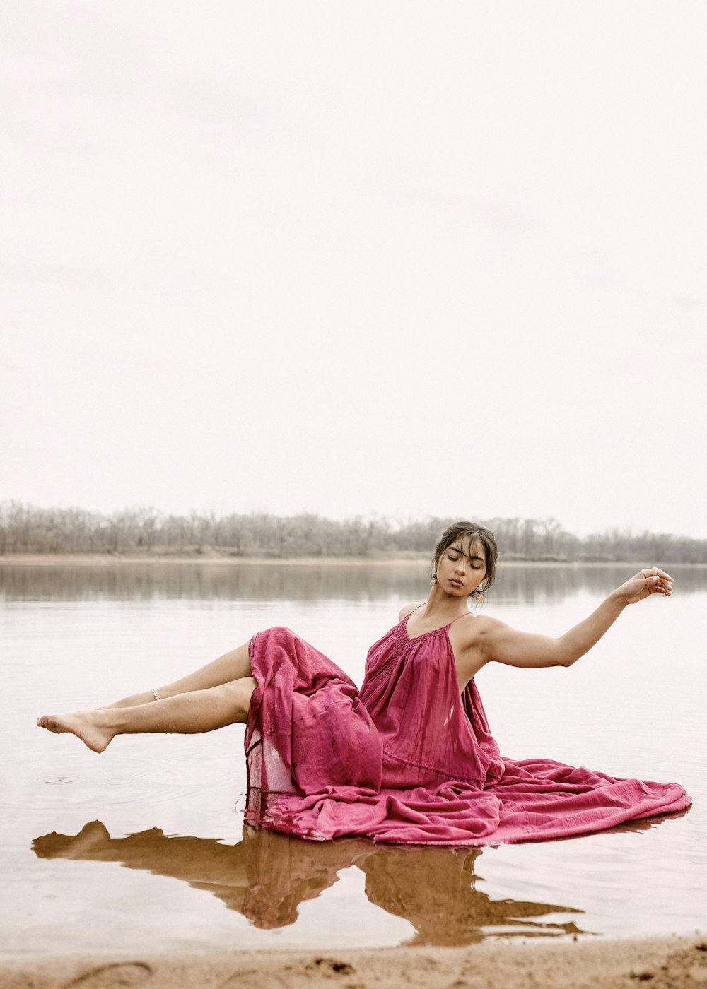 a woman in a dress lying on the beach