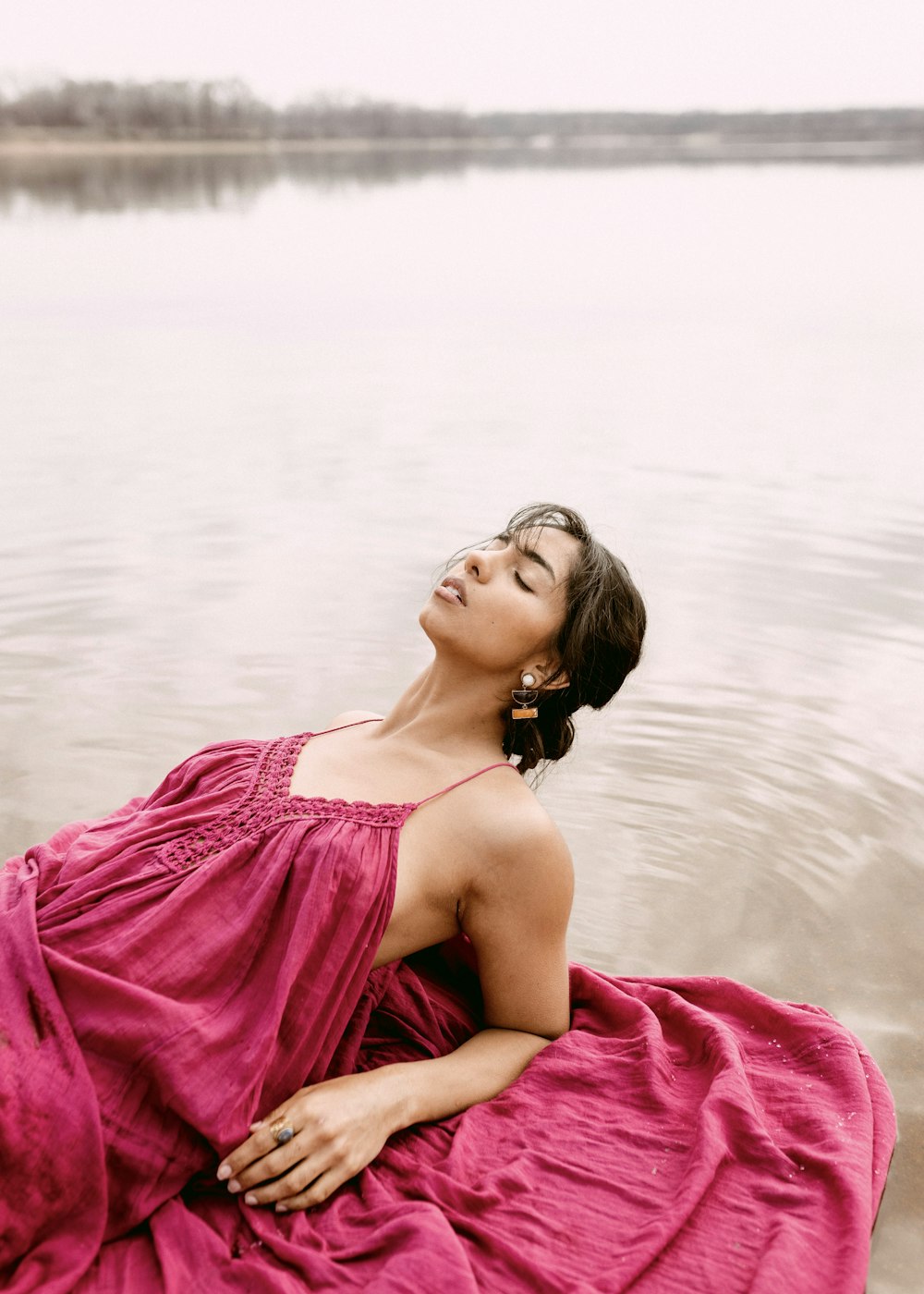 a woman in a pink dress lying on a beach