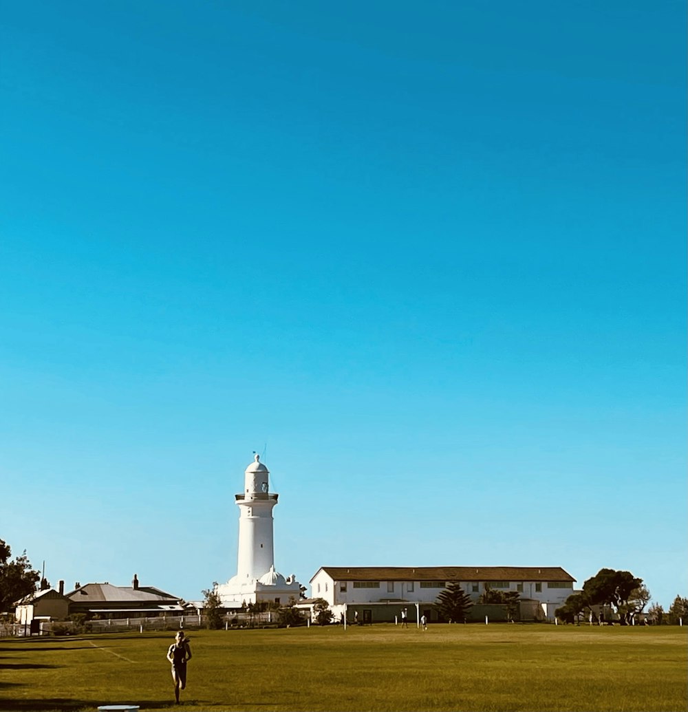 a person standing in a field with a lighthouse in the background