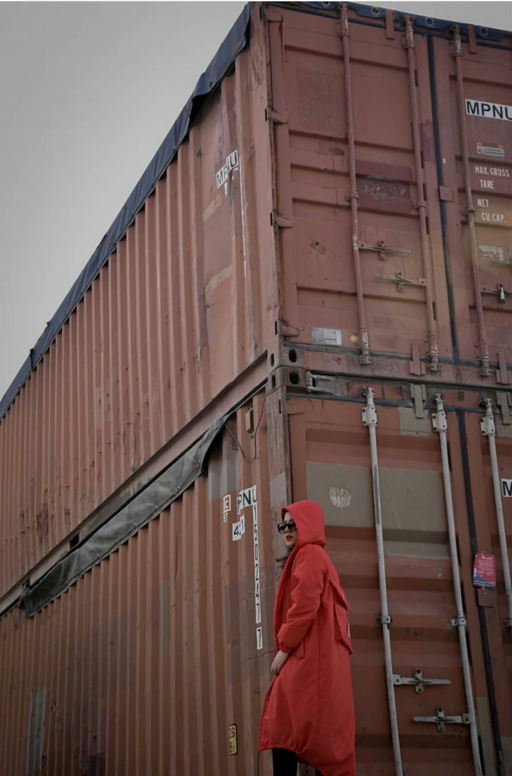 a person in a red robe standing next to a large container