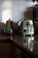 Close-up of a stainless steel toaster and kettle set on a kitchen shelf.