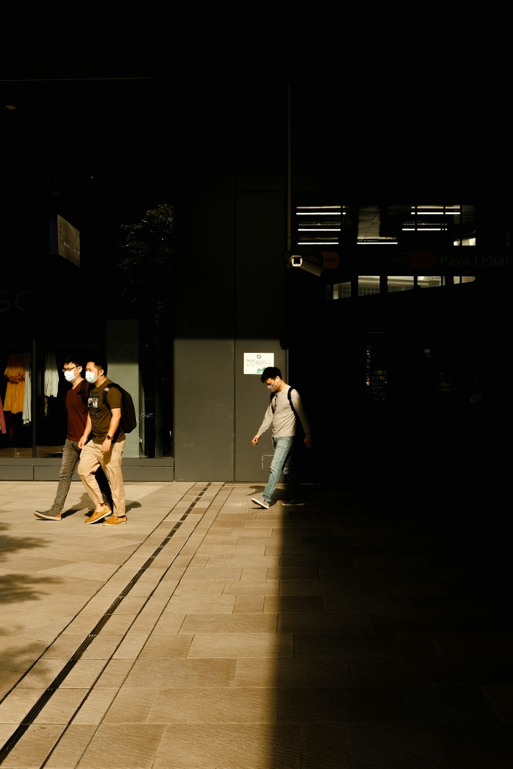 a group of people walking on a sidewalk at night