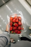 a hand holding a container of strawberries