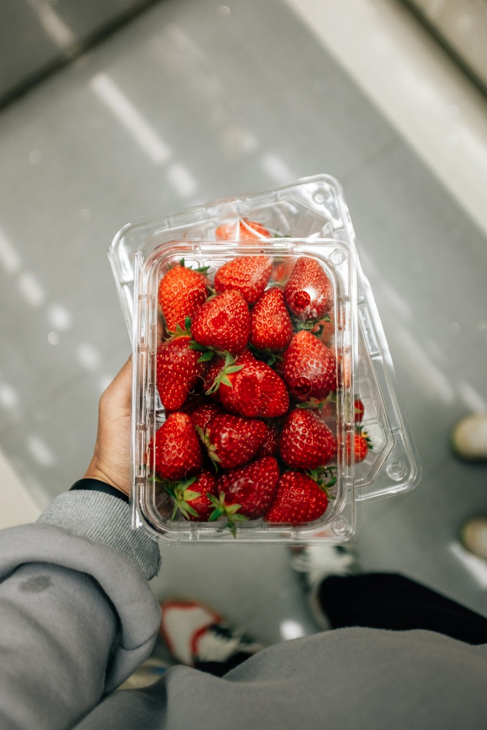 una mano che tiene un contenitore di fragole