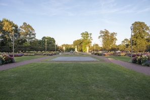 A vibrant public park area with well-maintained lawns and artistic garden lighting at dusk.