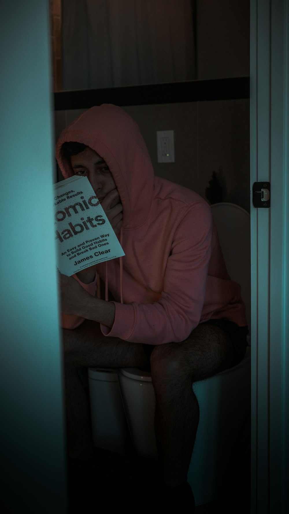 a man wearing a pink shirt and holding a book
