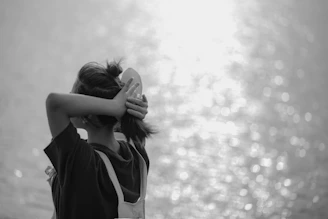 a woman with her hands behind her head, looking off into the distance