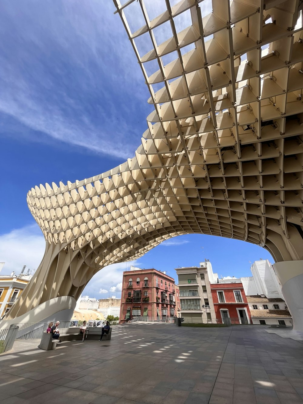a large glass building with a curved roof with Metropol Parasol in the background