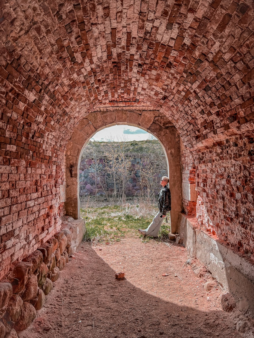 a person walking through a stone tunnel