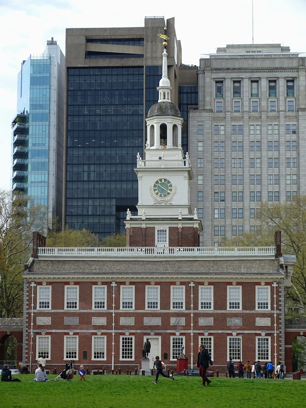 a large brick building with a clock tower with Independence Hall in the background