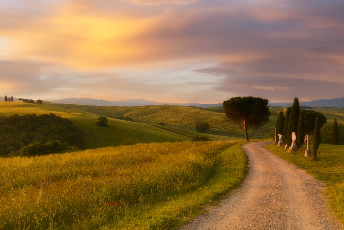 Rolling Tuscany hills with cypress trees and farmhouse at golden hour