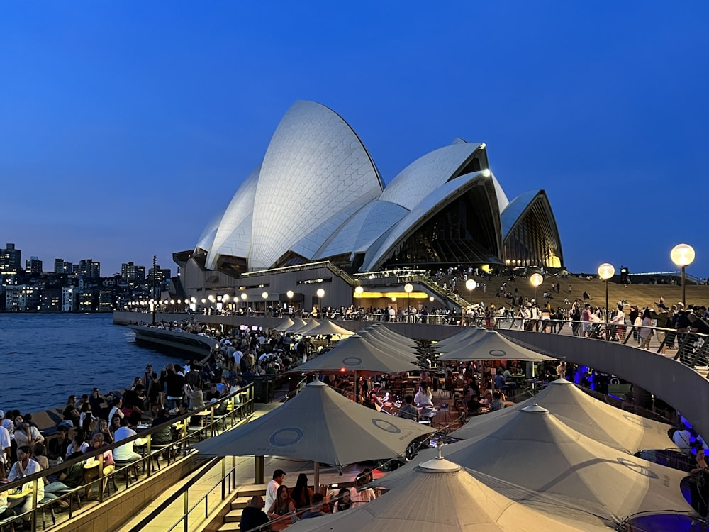 a large crowd of people at a concert with Sydney Opera House in the background