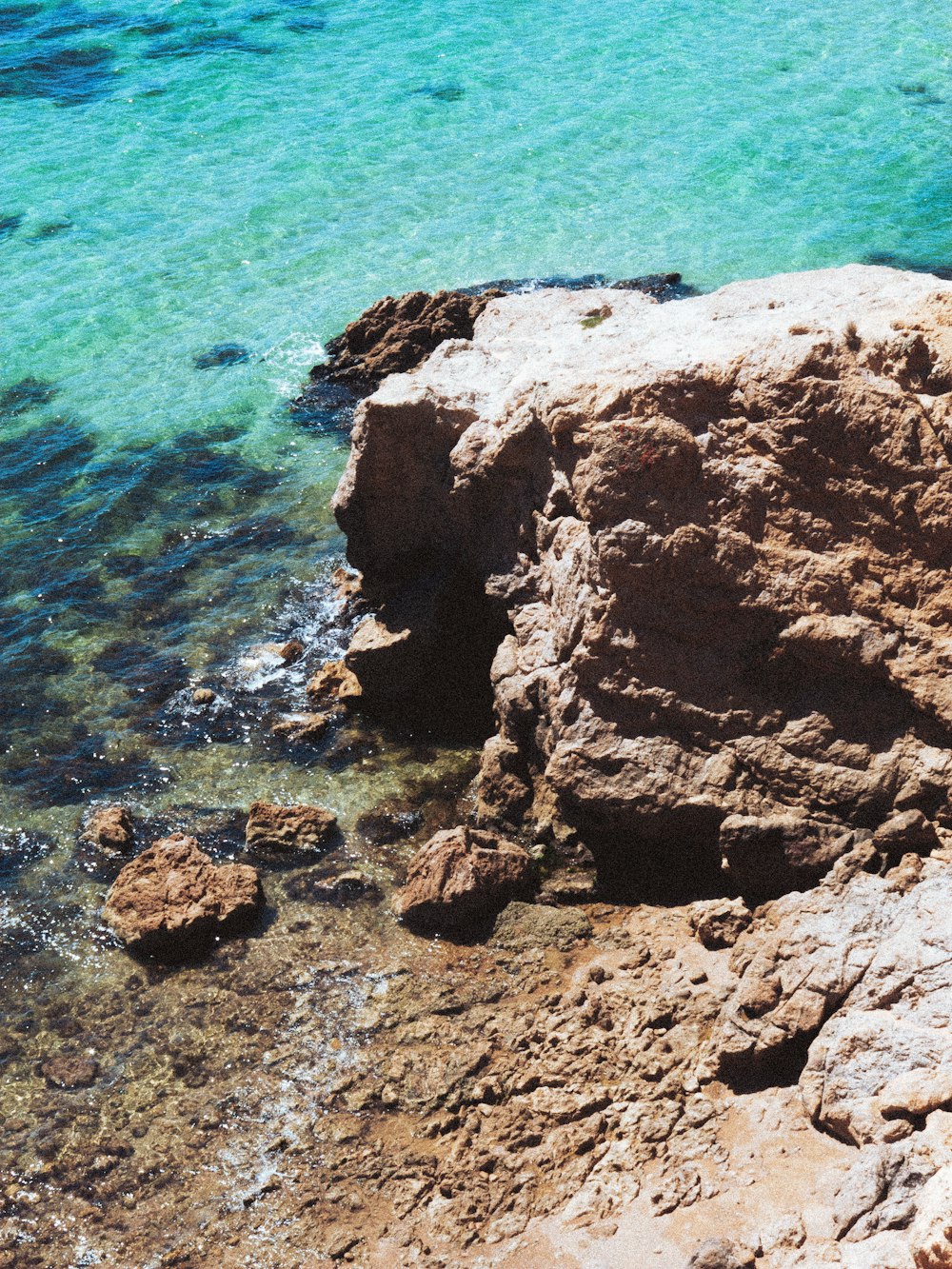 a rocky beach with a body of water in the background