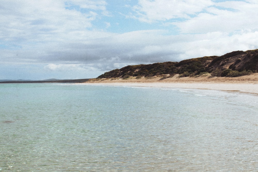 a beach with a hill in the background