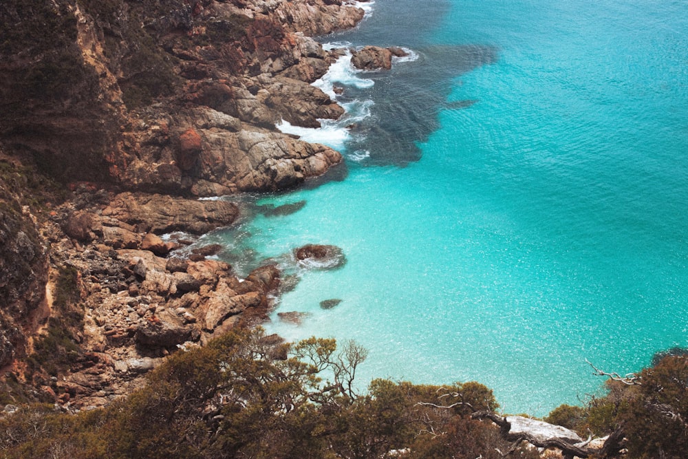 a rocky beach with a body of water in the background