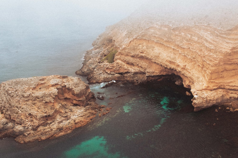 a rocky cliff with a body of water below